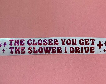 May include: White sticker with pink glitter lettering that reads "The closer you get, the slower I drive".