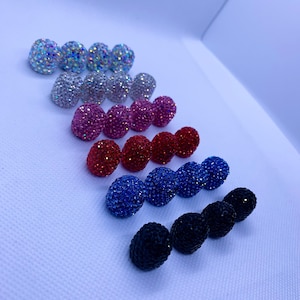 May include: A set of 10 pairs of rhinestone earrings in various colors, including iridescent, silver, pink, red, blue, and black.