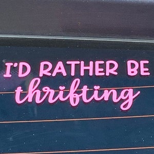 May include: Pink vinyl sticker on a car window that reads "I'd rather be thrifting".