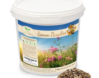 Puede incluir: Un cubo de plástico blanco que contiene 1kg de semillas de flores etiquetado como Bienen Paradies. La etiqueta muestra una abeja dibujada, un campo de tréboles rosas y texto con instrucciones de plantación para 300 a 500 m².