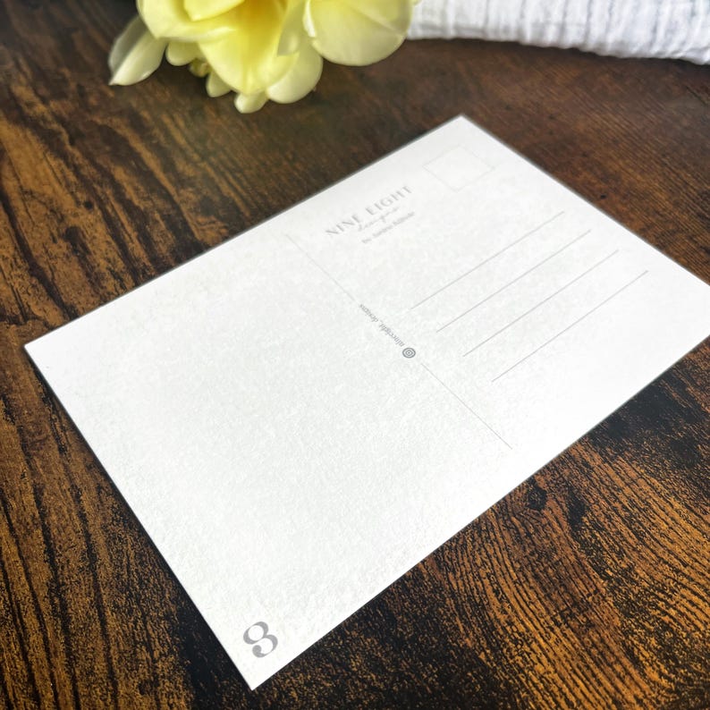 May include: A white rectangular postcard with a textured surface. The back features a stamp box, address lines, and the text NINE EIGHT designs by Sarah Spink. A small number 8 is printed in the bottom left corner and a social media handle is included.