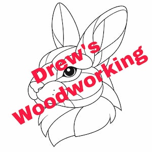 May include: A black and white line drawing of a rabbit's head, featuring geometric shapes. The text "Drew's Woodworking" is printed in red diagonally across the image. The rabbit has large ears and a detailed eye.