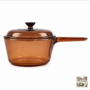 May include: A translucent amber-coloured glass saucepan with a matching lid and a long, integrated handle. The cookware features a smooth, rounded body and a circular knob on the centre of the lid. The glass is clear, allowing light to pass through.