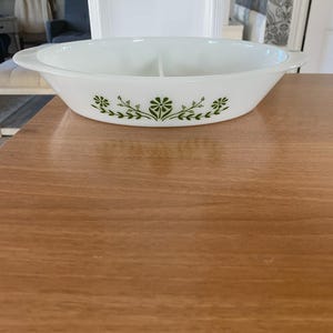 Peut inclure: Un plat de service blanc divisé avec un motif floral vert. Le plat ovale comporte deux compartiments et des poignées à chaque extrémité. Le motif floral vert est un motif répétitif de fleurs et de feuilles.