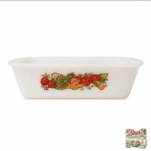 May include: A rectangular white milk glass loaf pan featuring a colourful vegetable illustration on the front. The design includes red tomatoes, orange carrots, green lettuce, and onions. The dish has smooth, sloped sides and a wide rim.