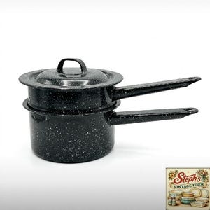 May include: A black double boiler pot with a white speckled enamel finish. The set includes a bottom pot and a top insert, both featuring long handles and a matching lid. A small logo in the corner reads Steph's VINTAGE FINDS.