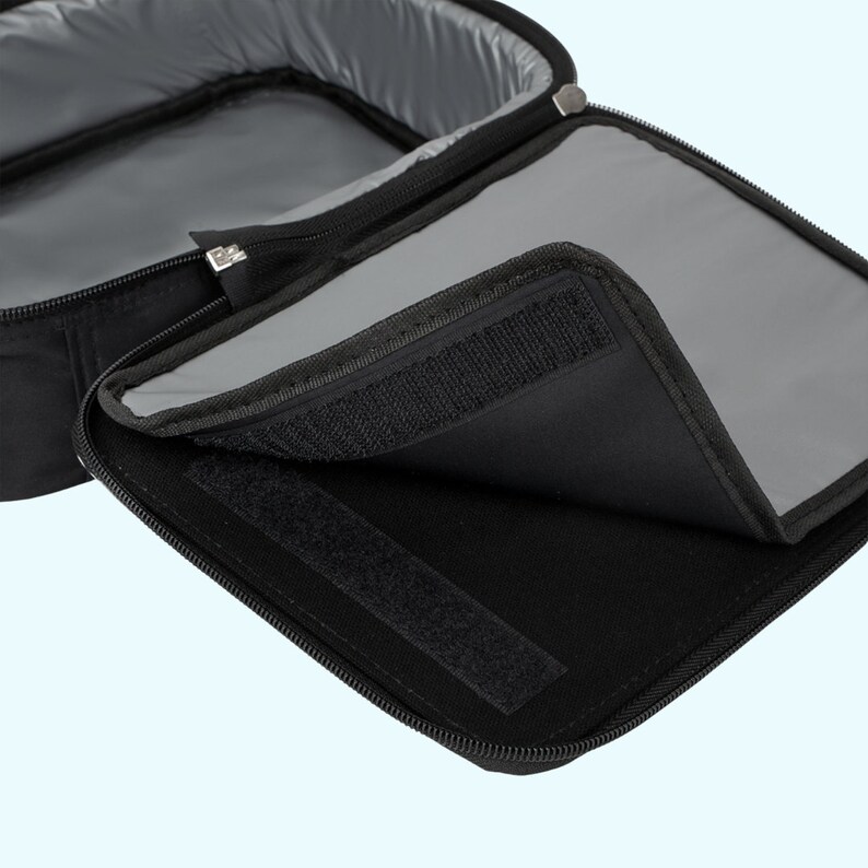 Op de afbeelding: Zwarte ge&iuml;soleerde lunchtas met een ritssluiting en een klittenbandsluiting. De tas is open om een ​​grijze voering te laten zien.