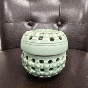 May include: A light mint green ceramic jar with a removable lid. The jar features a repeating geometric pattern of raised star-like points and circular cutouts throughout the body and the lid, finished with a glossy, crackled glaze texture.