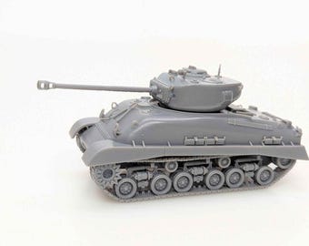 May include: A gray model tank with a long barrel and detailed tracks. The miniature tank is a replica of a military vehicle, showcasing its turret and wheels. The model is made of plastic and sits on a white surface.