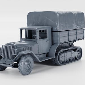Op de afbeelding: Een grijs model van een vintage militaire vrachtwagen met een met canvas bedekte laadbak. De vrachtwagen heeft voorwielen en rupsbanden achter, een cabine met ramen en een gedetailleerde grille. Het model is een gedetailleerde replica.