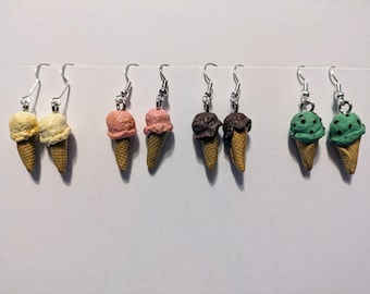 Puede incluir: Seis pares de pendientes colgantes con conos de helado en miniatura en varios sabores: vainilla, fresa, chocolate y chocolate con menta.
