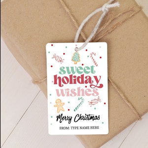 May include: A white rectangular gift tag with the text "sweet holiday wishes" in green, red, and pink. The tag is decorated with candy cane, gingerbread man, and Christmas tree illustrations. The words "Merry Christmas" and "FROM: TYPE NAME HERE" are also printed on the tag. The tag is tied to a wrapped package.