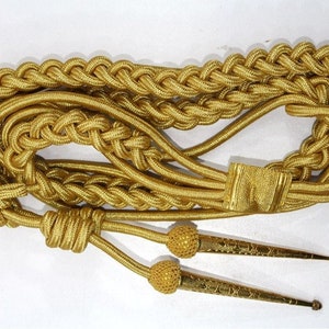 May include: A gold braided cord with two gold tassels. The cord is used for ceremonial purposes.