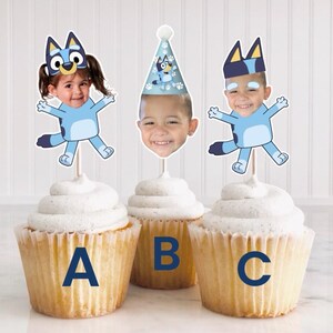 Peut inclure: Trois cupcakes d&eacute;cor&eacute;s de figurines bleues et blanches repr&eacute;sentant un personnage avec le visage d'un enfant. Les figurines sont tir&eacute;es du dessin anim&eacute; Bluey. Les cupcakes sont &eacute;tiquet&eacute;s A, B et C.