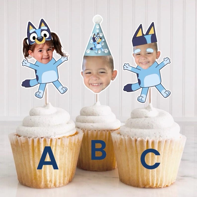 Peut inclure: Trois cupcakes d&eacute;cor&eacute;s de figurines bleues et blanches repr&eacute;sentant un personnage avec le visage d'un enfant. Les figurines sont tir&eacute;es du dessin anim&eacute; Bluey. Les cupcakes sont &eacute;tiquet&eacute;s A, B et C.