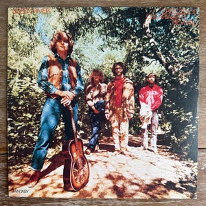 May include: Album cover featuring the band Creedence Clearwater Revival. The band members are standing in a forest setting. One member holds a guitar. The album title "Freedom of Clearwater Revival" is visible.