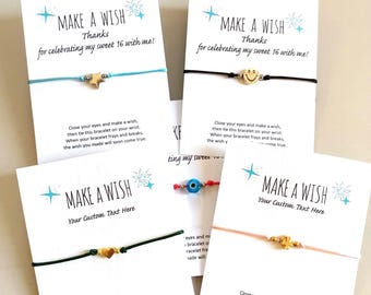 May include: Four wish bracelets on white cards with blue star graphics and text. One card features a light blue cord with a star charm, another a black cord with a smiley face, a dark green cord with a heart, and a peach cord with a clover charm.