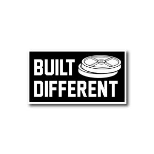 Może przedstawiać: Czarno-biała naklejka z tekstem "BUILT DIFFERENT" i białym obrysem talerza do ćwiczeń.