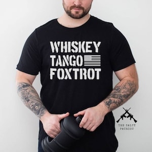 May include: Black t-shirt with white text that reads "Whiskey Tango Foxtrot" and a small American flag. The text is in a military font. The shirt also has a small logo on the bottom right that reads "The Salty Patriot".