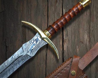 May include: A detailed image of a sword with a patterned blade and a brown wooden handle. The sword features a gold-colored crossguard and a matching pommel. A brown leather sheath is visible in the lower right corner, with a decorative pattern.