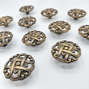 May include: A collection of round cabinet knobs featuring an antique brass finish. Each knob has an openwork design with a central circular element surrounded by an intricate, interwoven lattice pattern with curved, scroll-like edges.