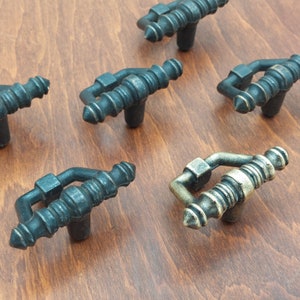 May include: Six antique-style cabinet knobs with a decorative design. The knobs are made of metal and have a black finish. Some of the knobs have a gold finish.