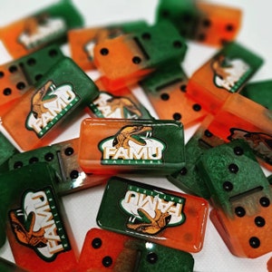May include: A collection of green and orange dominoes with the FAMU Rattlers logo and a snake graphic. The dominoes are made of a glossy material and have black dots on the sides.
