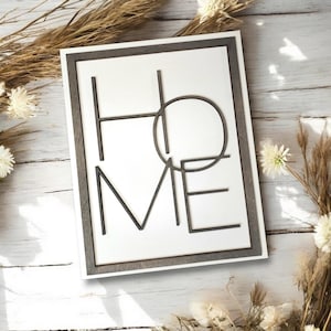May include: A white framed sign with the word "HOME" spelled out in black geometric shapes.