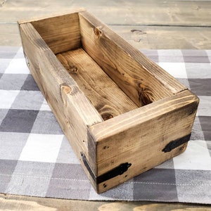 May include: A rectangular wooden box with a dark brown stain and metal accents. The box is empty and has a rustic look.
