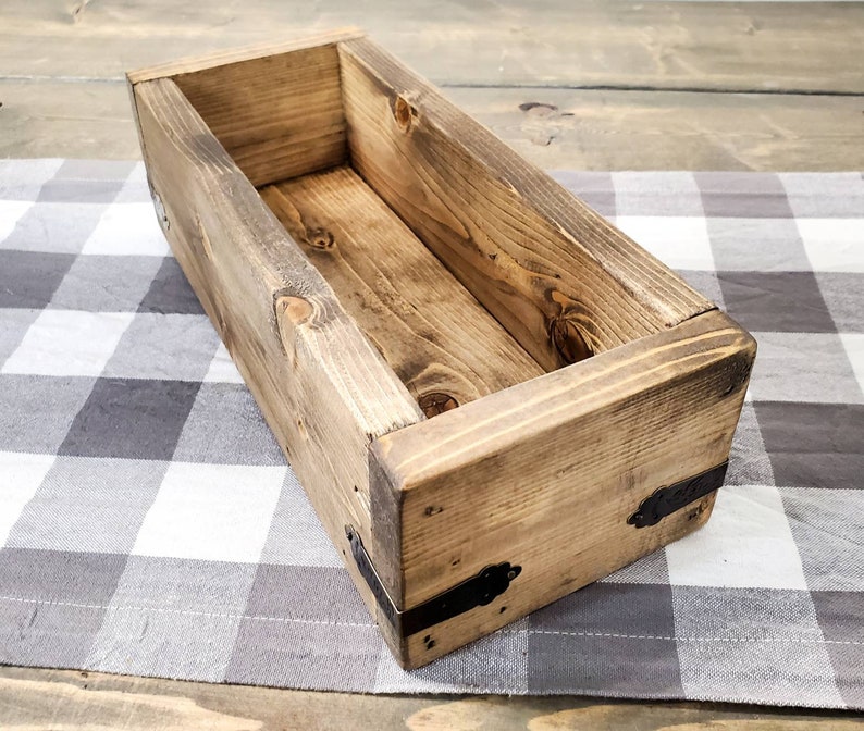 May include: A rectangular wooden box with a dark brown stain and metal accents. The box is empty and has a rustic look.