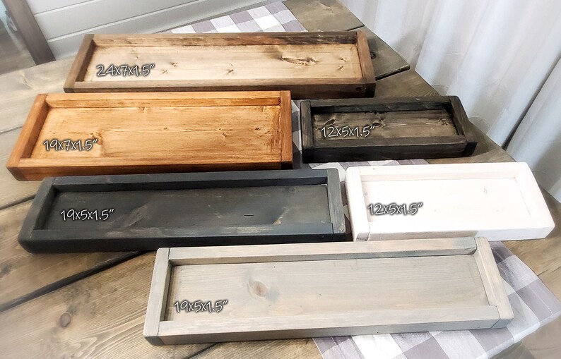 May include: Five wooden trays in different sizes and colours. The trays are 24x15 inches, 19x7x15 inches, 19x5x15 inches, 12x5x15 inches, and 12x5x15 inches. The trays are stained in various shades of brown, black, and white.
