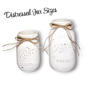 May include: Two white distressed Ball Mason jars of different heights, each featuring a brown twine bow tied around the neck. The text "Distressed Jar Sizes" appears above the jars, while the embossed "Ball" and "Mason" logos are visible.