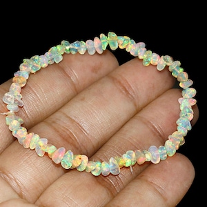 May include: A bracelet made of small, irregular opal gemstones. The opals show a variety of colours, including white, yellow, and touches of green and orange. The bracelet is strung together, creating a flexible and elegant piece of jewellery.