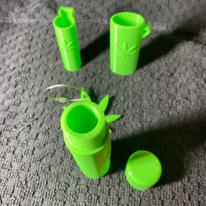 May include: A set of four green plastic containers with a leaf design. The containers are various sizes and shapes, including a round container with a lid, a tall cylindrical container, and a shorter cylindrical container with a handle.