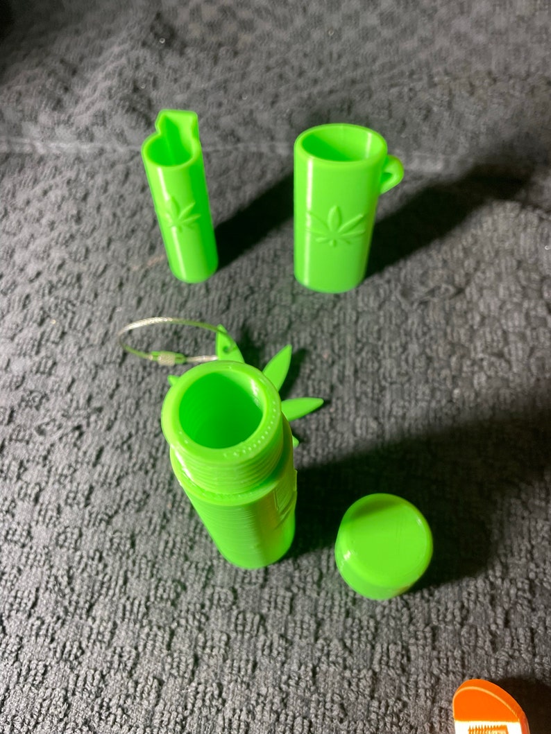 May include: A set of four green plastic containers with a leaf design. The containers are various sizes and shapes, including a round container with a lid, a tall cylindrical container, and a shorter cylindrical container with a handle.