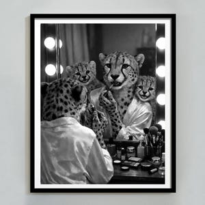 May include: Black and white framed print featuring cheetahs in a vanity scene. One cheetah applies makeup in front of a mirror, while others observe. The image has a vintage, humorous feel, with a focus on the cheetahs' expressions and the vanity setup.