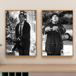 Puede incluir: Dos impresiones en blanco y negro enmarcadas de actores de una película navideña. Una muestra a un hombre con un suéter sosteniendo una motosierra, la otra a un hombre sosteniendo un cable con una expresión de sorpresa. Ambos están en marcos dorados.