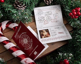 May include: A festive scene featuring a red and white candy cane, a burgundy "Lapland Passport," and a passport with stamps from various cities. The passport includes a photo of Santa Claus. The scene is decorated with pine branches, pine cones, and red berries.