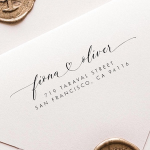 May include: Two pale pink envelopes, each sealed with a gold wax seal. One envelope is printed with the names "fiona & oliver" and an address in black ink. The seals feature a tree design, enhancing the stationery's elegance.