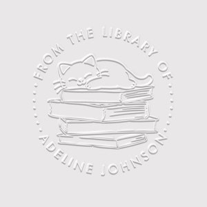 May include: A white embossed stamp with the text "From the Library of Adeline Johnson" and a cartoon of a cat sleeping on a stack of books.
