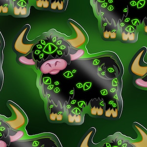 Op de afbeelding: Een zwarte en groene sticker met een cartoonillustratie van een yak met meerdere groene ogen. De yak heeft een roze neus en staat op alle vier poten.