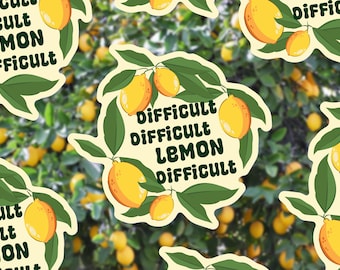May include: A sticker with a lemon branch design, displaying yellow lemons and green leaves. The text "Difficult Lemon Difficult" is in dark green. The background is a blurred image of a lemon tree.