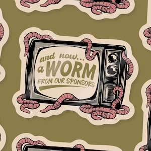 Op de afbeelding: Een sticker met een vintage televisie met de tekst "and now... a WORM from our sponsors". Roze wormen kruipen rond de tv. De achtergrond is een gedempt olijfgroen.