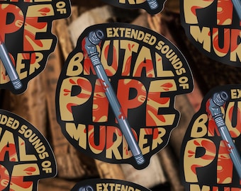 May include: A circular sticker featuring the text EXTENDED SOUNDS OF BRUTAL PIPE MURDER in bold tan letters against a black background. A grey metal pipe with red splatters is positioned diagonally across the centre of the design.