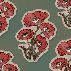 Op de afbeelding: Vel met stickers met een herhalend patroon van rode klaprozen, elk met een oogvormig centrum. De bloemen staan tegen een gedempte groene achtergrond. De sticker randen zijn licht beige van kleur.