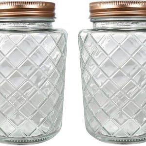 May include: Two clear glass jars featuring a textured diamond pattern across the exterior surface. Each jar is topped with a metallic copper-colored screw-top lid with a ribbed edge. The jars have a cylindrical shape with a wide mouth opening.