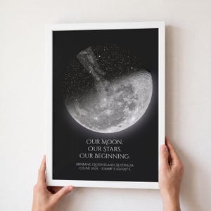 May include: A framed wall art print featuring a black background with a circular moon and star field graphic. The text reads: OUR MOON. OUR STARS. OUR BEGINNING. BRISBANE, QUEENSLAND, AUSTRALIA 17 JUNE 2025 -27.4698 S 153.0251 E in white lettering.