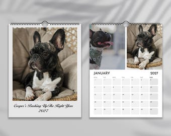 Op de afbeelding: Een wandkalender voor 2027 met een gestroomde en witte Franse Bulldog. De omslag toont de hond en de tekst Cooper's Barking Up The Right Year 2027. De januaripagina bevat twee foto's van de hond en een kalenderoverzicht voor januari 2027.
