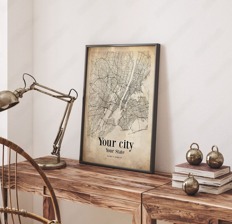 May include: A black framed print of a vintage style map of a city with the text "Your city" and "Your State" below the map.