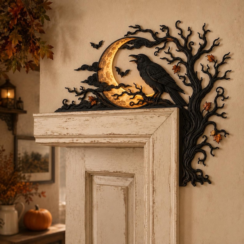 May include: A black wall decoration featuring a crescent moon with a textured surface, a perched raven, and bare tree branches. Small bats are positioned near the moon, and orange autumn leaves are scattered among the dark, twisted tree limbs.